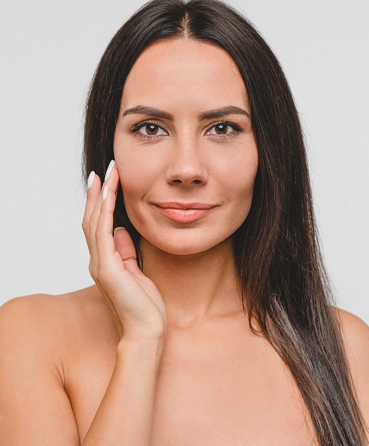 Woman touching her face with a gentle smile.