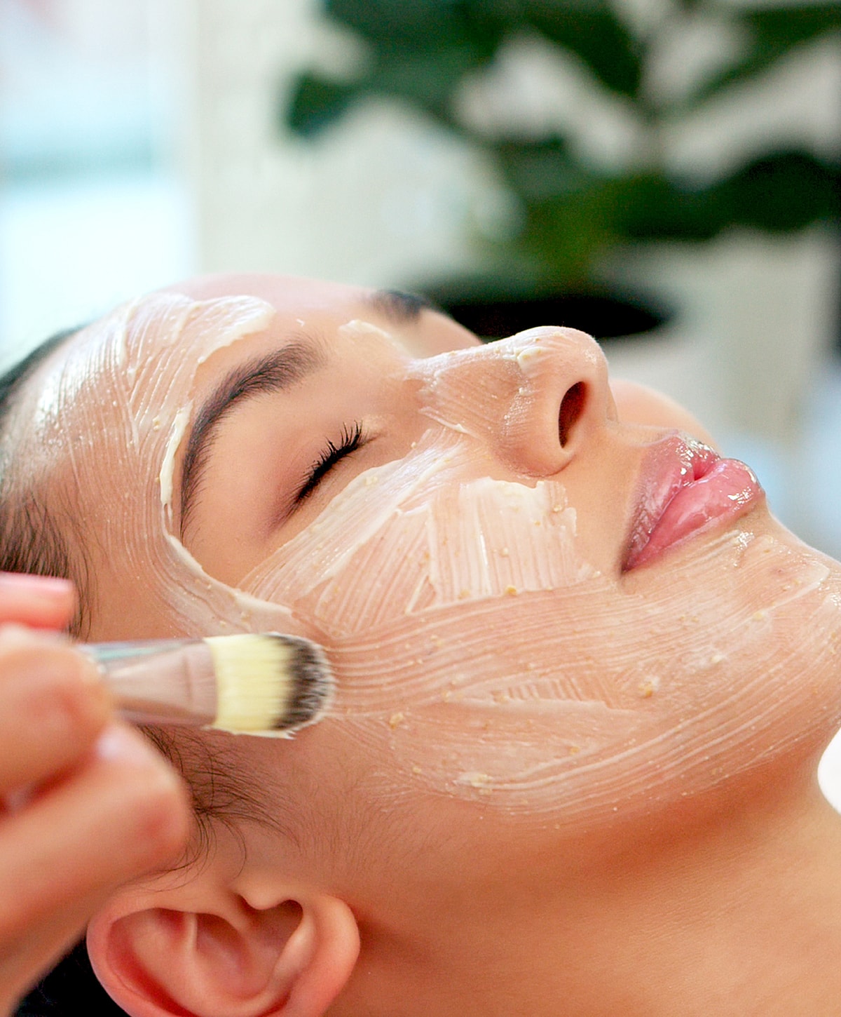 Applying facial mask with brush on relaxed skin.