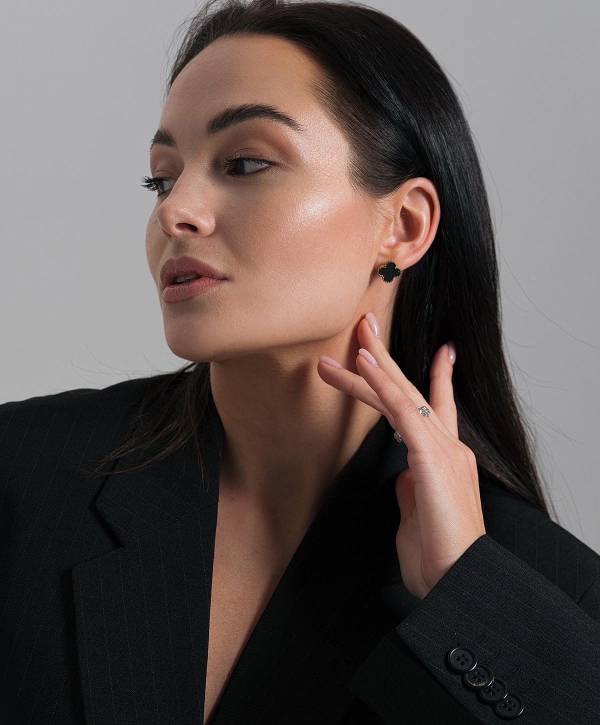 Woman in blazer showcasing jewelry and beauty.