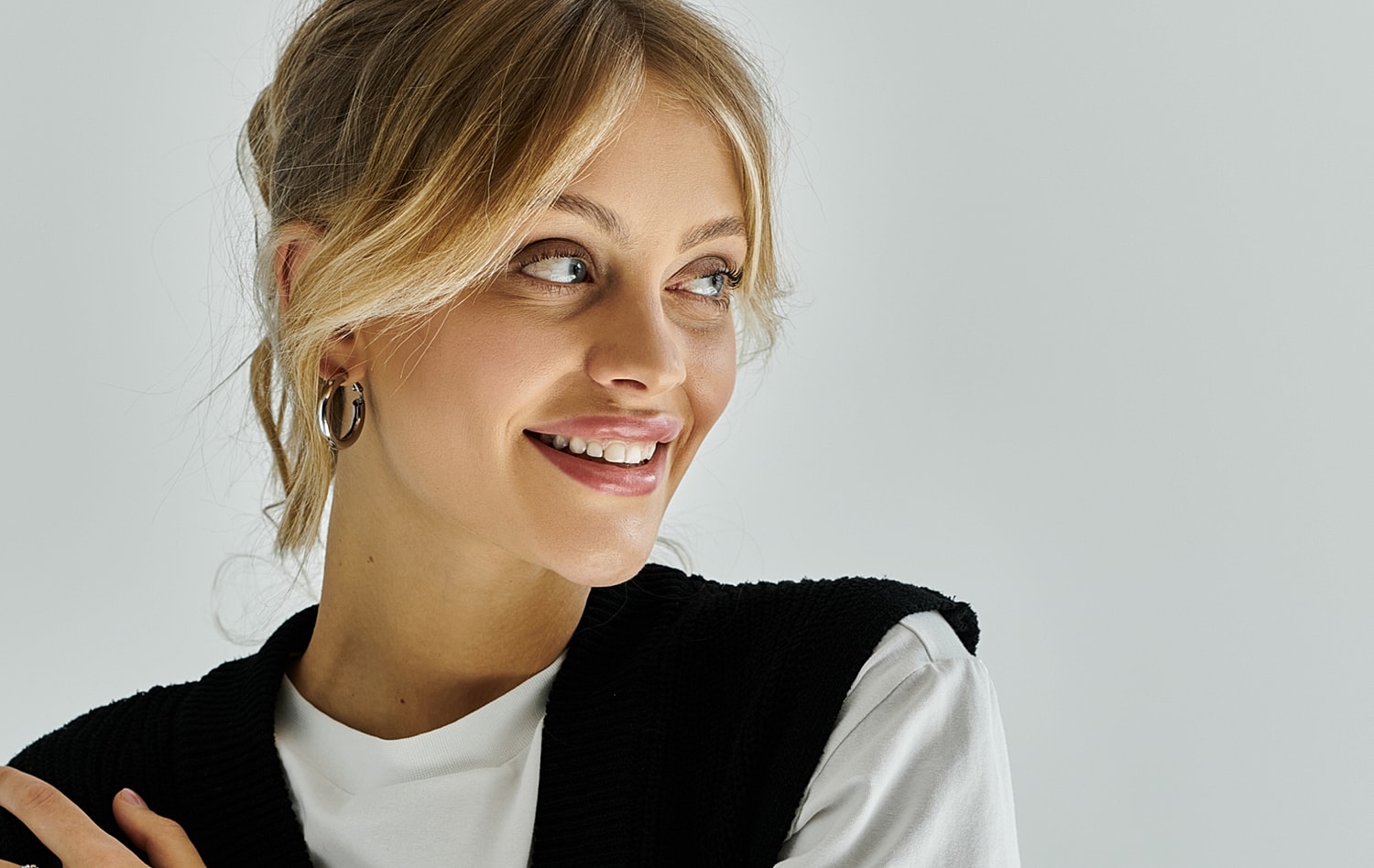 Smiling woman with blonde hair and earrings.