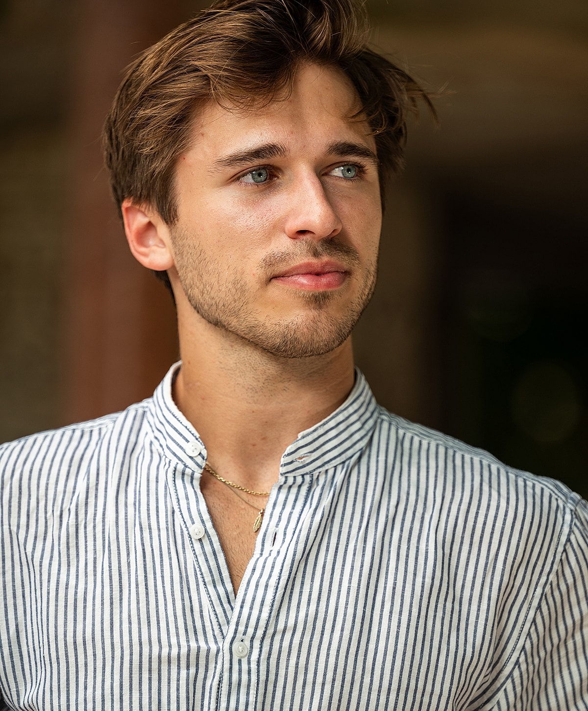 Young man in striped shirt looking thoughtfully.