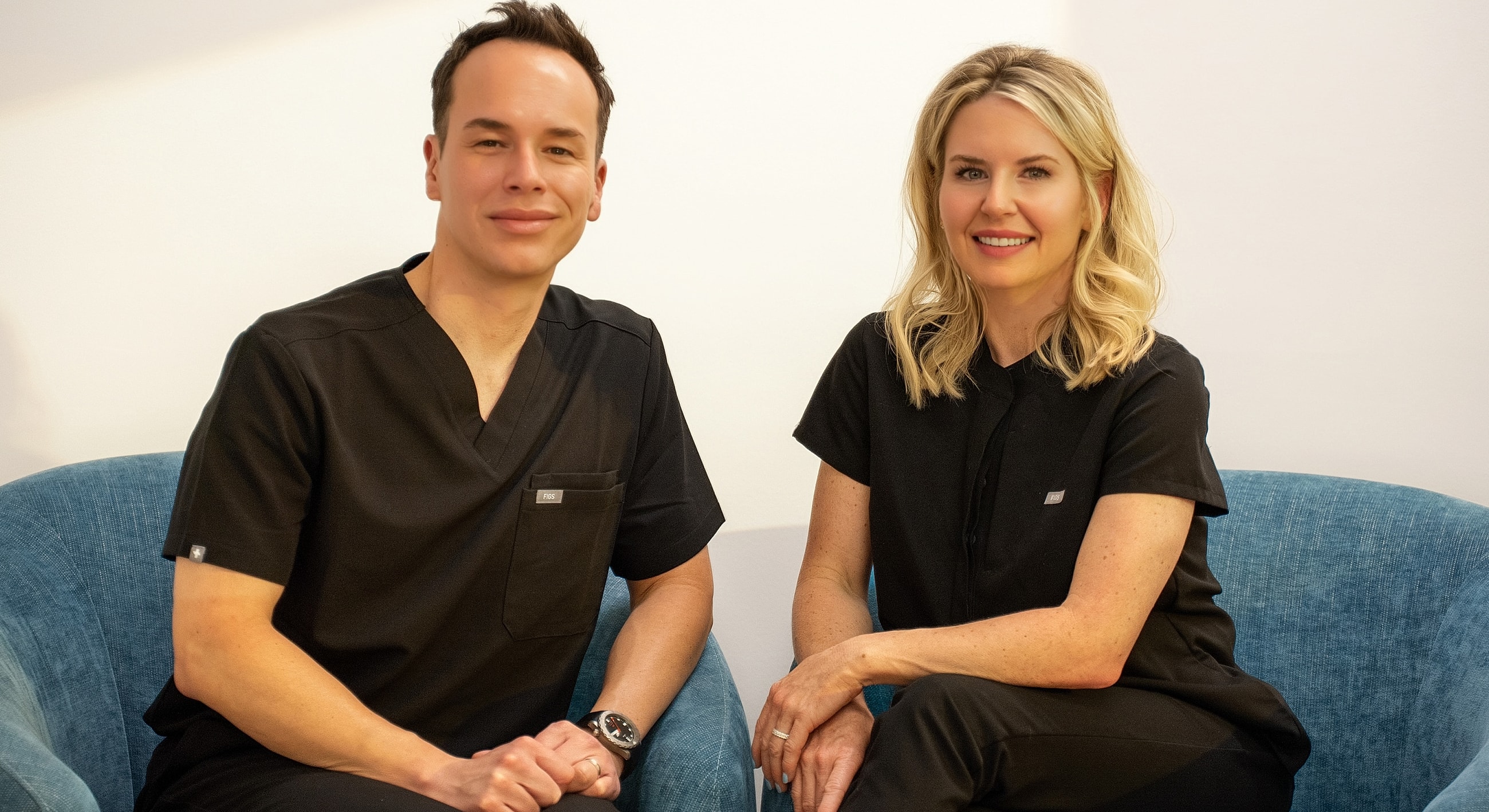 Two professionals in matching black attire, smiling.