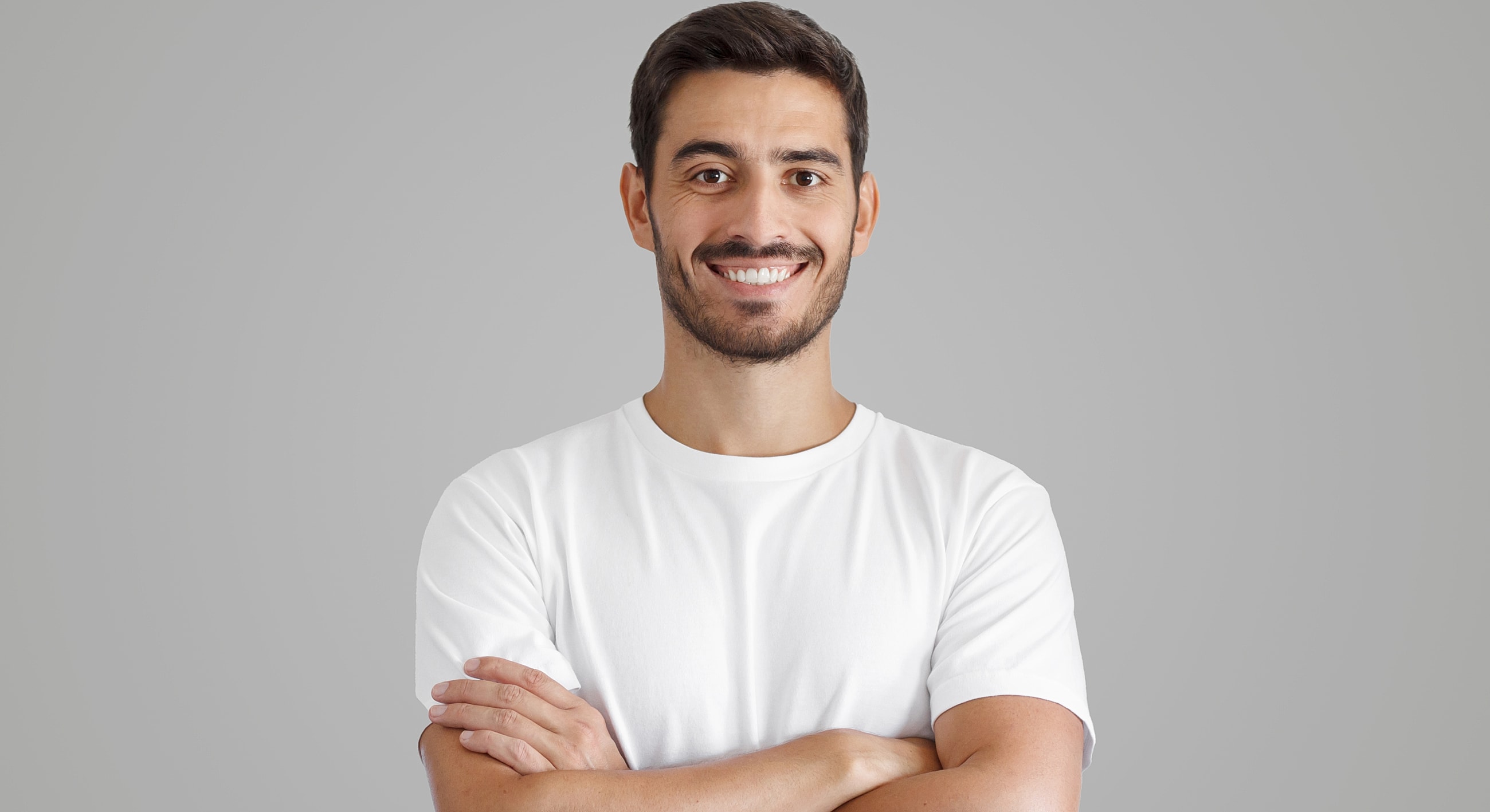 Smiling man in white t-shirt with crossed arms.